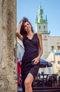 Young charming woman with long curly hair, strolling among the old town of Lviv architecture in black dress Royalty Free Stock Photo