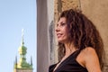 Young charming woman with long curly hair, strolling among the old town of Lviv architecture in black dress Royalty Free Stock Photo