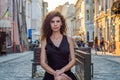 Young charming woman with long curly hair, strolling among the old town of Lviv architecture in black dress Royalty Free Stock Photo