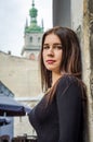 Young charming woman with long curly hair, strolling among the old town of Lviv architecture in black dress Royalty Free Stock Photo