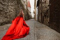 Young gorgeous woman in long red dress walking in Medieval town Royalty Free Stock Photo