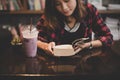 Young charming woman with milkshake and reading book sitting ind Royalty Free Stock Photo