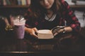 Young charming woman with milkshake and reading book sitting ind Royalty Free Stock Photo