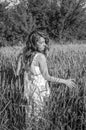 Young charming woman walking outdoors in a field near the green bushes and trees, hand patting ptsenitsy ears, dressed in a Royalty Free Stock Photo