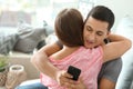 Young cheater texting lover while hugging his girlfriend at home