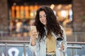 Young cheerfful woman using smartphone and drinking take away coffee in paper cup. Stylish woman at cafe indoors. Royalty Free Stock Photo