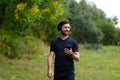 Young cheerful active guy sporty walking with headphones mobile phone enjoying listening to music, jogging outdoors on urban city Royalty Free Stock Photo