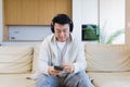 cheerful asian guy listening to music in headphones sitting on sofa at home. A man alone on the couch feels good lifestyle. Royalty Free Stock Photo