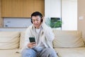 cheerful asian guy listening to music in headphones sitting on sofa at home. A man alone on the couch feels good lifestyle. Royalty Free Stock Photo