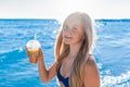 Young, cheerful attractive girl blonde of European appearance teenager in a blue swimsuit with a colored non-alcoholic cocktail in Royalty Free Stock Photo