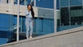 Young cheerful beautiful brunette business woman winner carefree girl walking on urban blue glass building background Royalty Free Stock Photo