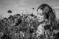 A young cheerful beautiful girl walks in a poppy meadow among red blooming poppies on a bright, hot, sunny summer day Royalty Free Stock Photo