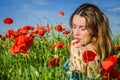 A young cheerful beautiful girl walks in a poppy meadow among red blooming poppies on a bright, hot, sunny summer day Royalty Free Stock Photo