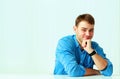 Young cheerful businessman in blue shirt sitting at the table