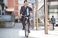 Young cheerful businessman riding a bicycle and using phone Royalty Free Stock Photo