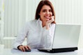 Young cheerful businesswoman sitting at the table on her workplace Royalty Free Stock Photo