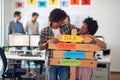 Young cheerful colleagues are holding a sign with company slogans and posing for a photo in the office. Employees, job, office Royalty Free Stock Photo