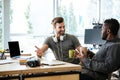 Young cheerful colleagues sitting in office talking with each other. Royalty Free Stock Photo