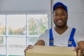 Young cheerful contractor man helps to make home move, carries boxes with things