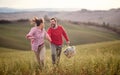 A young cheerful couple enjoying running over a large meadow while holding by hands. Love, relationship, together, nature Royalty Free Stock Photo