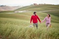 A young cheerful couple feeling happy while walking a large meadow together. Love, relationship, together, nature Royalty Free Stock Photo