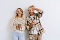 Young cheerful couple gesturing holding smartphones while standing isolated