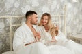 Young and cheerful couple having a breakfast drinking coffee while sitting together on the bed at home Royalty Free Stock Photo
