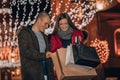 Young cheerful couple holding presents in a shopping bags and having fun at the Christmas night in the city street Royalty Free Stock Photo