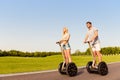 Young cheerful couple in love driving segways and smiling in park Royalty Free Stock Photo