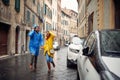 A young cheerful couple in raincoats is running away from the rain while walking the city. Walk, rain, city, relationship Royalty Free Stock Photo