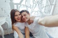 Young cheerful couple taking selfie pictures with a smart phone in bedroom. Celebrating Saint Valentine`s day together Royalty Free Stock Photo