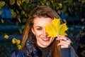 Young cheerful cute girl woman playing with fallen autumn yellow leaves in the park near the tree, laughing and smiling Royalty Free Stock Photo