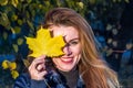 Young cheerful cute girl woman playing with fallen autumn yellow leaves in the park near the tree, laughing and smiling Royalty Free Stock Photo