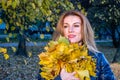 Young cheerful cute girl woman playing with fallen autumn yellow leaves in the park near the tree, laughing and smiling Royalty Free Stock Photo