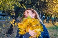 Young cheerful cute girl woman playing with fallen autumn yellow leaves in the park near the tree, laughing and smiling Royalty Free Stock Photo