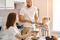 Young cheerful daddy tossing pancakes in the kitchen