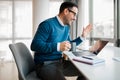 Cheerful entrepreneur waving while video conferencing on laptop at office desk Royalty Free Stock Photo