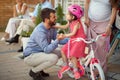 Young cheerful father buying new bicycle for little girl in bike shop