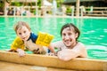 Young cheerful father and son in a swimming pool