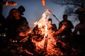 Young and cheerful friends sitting and fry marshmallows near bonfire in the night Royalty Free Stock Photo