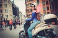 Young cheerful girl near scooter in in european city