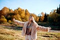 Cheerful girl with raised hands on the field in warm autumn season. Royalty Free Stock Photo