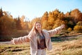 Cheerful girl with raised hands on the field in warm autumn season. Royalty Free Stock Photo