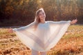 Cheerful girl with raised hands on the field in warm autumn season. Royalty Free Stock Photo