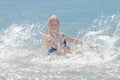 Young cheerful girl teenager blonde European appearance makes splashes of water with her hands in the sea Royalty Free Stock Photo