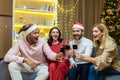 young cheerful group people, friends celebrate New Year countdown at home clink wine glasses while sitting on sofa at Royalty Free Stock Photo