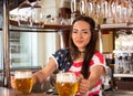 Young cheerful happy bartender girl offering two beers to custom