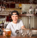 Young cheerful happy bartender offering beer to customer.