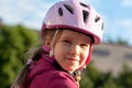 Young cheerful happy biker girl, little cyclist, child in a protective helmet on the bike smiling, portrait, face closeup Royalty Free Stock Photo