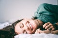 Young cheerful happy girl with a beautiful white-toothed smile lying with closed eyes on the bed